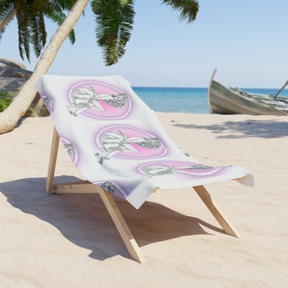 Beach towel with pink and green design on a wooden chair on a sandy beach with palm trees and ocean in the background.